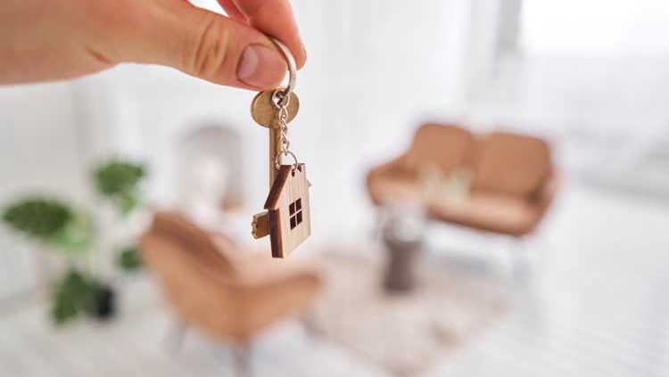homme tenant une clé et un porte clé de maison dans sa nouvelle propriété